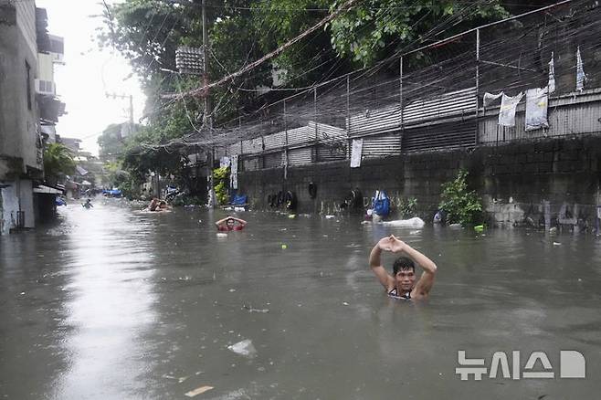 A man wades along chest-deep floods at a residential area after Tropical Storm Wipha caused intensified monsoon rains in Quezon city, Philippines, on Monday, July 21, 2025. (AP Photo/Aaron Favila)