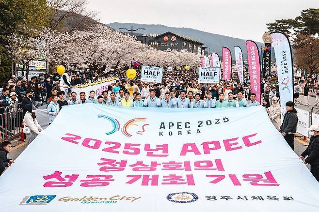 2025 APEC 정상회의 성공 개최를 기원하며 열린 경주 벚꽃마라톤대회 참가자들이 대형 현수막을 펼치고 응원의 메시지를 전하고 있다.