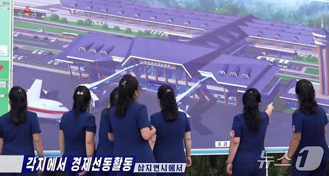지난 18일 조선중앙TV 보도에는 선전음악단이 '삼지연국제비행장'을 묘사한 3D 렌더링 디스플레이를 가리키고 있는 모습이 담겼다.(조선중앙TV 갈무리).