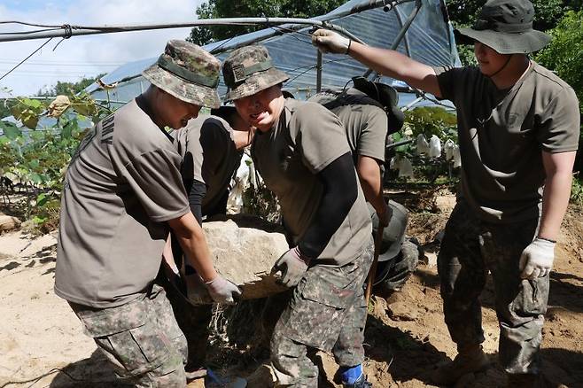 23일 경기도 가평군 상면 수해 지역에서 육군 수도기계화보병사단 혜산진여단 장병들이 중장비 진입이 불가능한 포도밭을 덮친 암반석을 치우고 있다. 연합뉴스