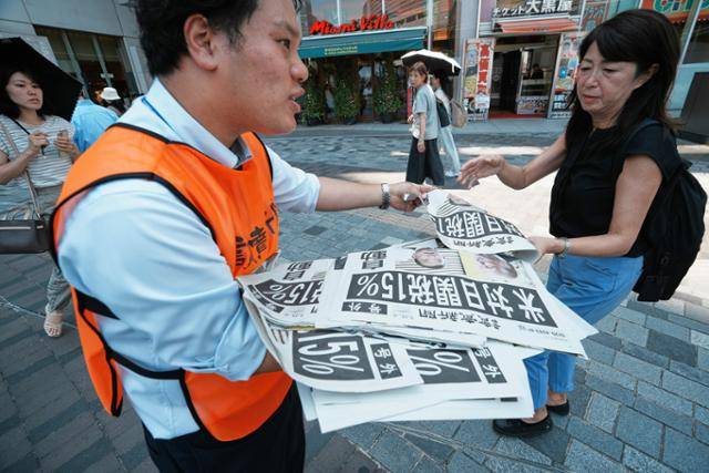요미우리신문 관계자가 일본 도쿄 시내에서 미국과 일본이 무역 협상을 타결했다는 내용의 호외를 나눠주고 있다. 도쿄=AP 연합뉴스