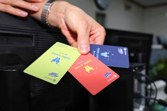 민생회복 소비쿠폰 지급 사흘째인 23일 광주 서구 농성1동 행정복지센터에서 한 직원이 서로 다른 색상의 현물 카드를 들고 있다. 광주=연합뉴스