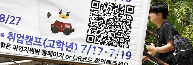 22일 서울의 한 대학 캠퍼스에 걸려 있는 취업지원 안내 현수막 앞으로 대학생이 걸어가고 있다. [김호영 기자]