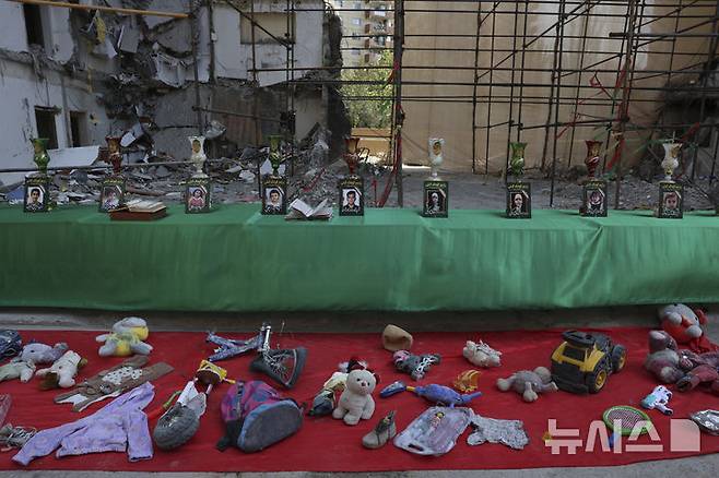 [테헤란=AP/뉴시스]지난달 13일 이스라엘의 이란 수도 테헤란 거주 지역 공습으로 숨진 어린이들의 사진이 전시돼 있다. 앞에는 어린이들이 인형과 책가방 등 가졌던 소지품들이 놓여 있다. 이란 정부가 민족주의를 자극하기 위해 광범위하게 노력하고 있다. 2025.7.23.