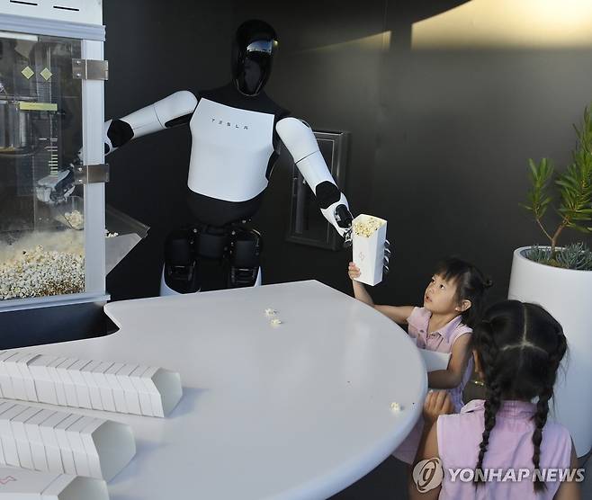 21일 테슬라 '다이너'에서 로봇 '옵티머스'가 어린이에게 팝콘을 건네는 모습 [UPI=연합뉴스. 재판매 및 DB 금지]