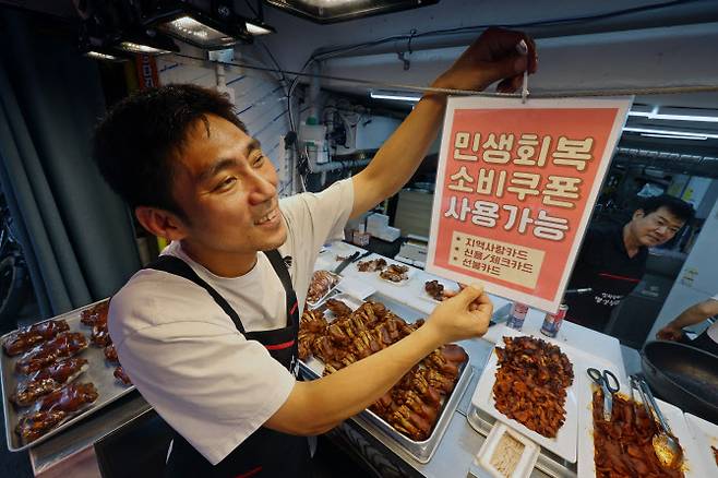 민생회복 소비쿠폰 1차 신청 첫 날인 21일 서울의 한 족발전문점에서 상인이 쿠폰 사용 관련 안내문을 붙이고 있다. (사진=뉴스1)