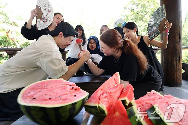 24일 오후 대구 달서구 계명대 성서캠퍼스 한학촌에서 열린 '외국인 유학생 여름나기' 행사에 참여한 학생들이 수박을 앞에 두고 팔씨름 한판을 벌이고 있다. 2025.7.24/뉴스1 ⓒ News1 공정식 기자