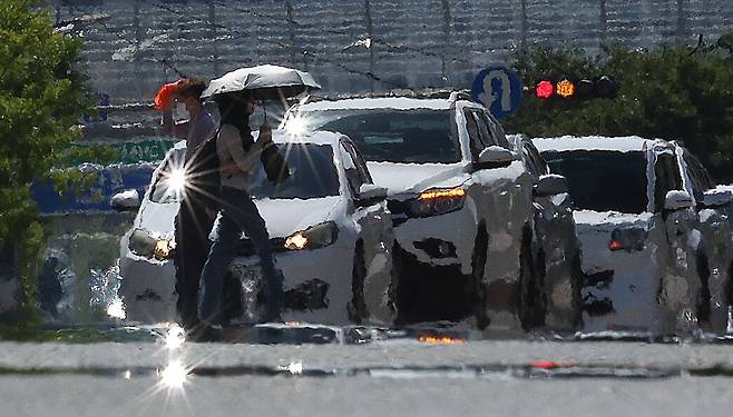 절기상 가장 덥다는 대서(大暑)에 대구지역에 폭염 경보가 발령된 지난 22일 대구 달서구 계명대학교 인근 도로가 지열로 달구어진 가운데 시민들이 양산과 옷가지 등으로 햇볕을 막으며 이동하고 있다. /연합뉴스