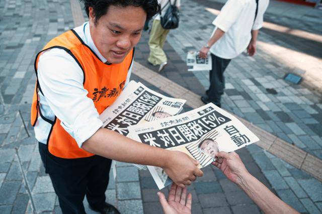 23일 일본 도쿄에서 요미우리 신문사의 한 직원이 도널드 트럼프 미국 대통령이 일본과 무역 협상을 완료했다는 내용을 보도한 신문 호외판을 배포하고 있다. 신문 1면에는 '미국, 일본에 15% 관세'라는 제목의 기사가 실렸다. 도쿄=AP, 뉴시스