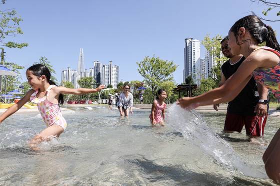 Children play in the infant pool at the Jamsil wading pool, with Lotte World Tower rising in the background. [KIM KYOUNG-ROK]