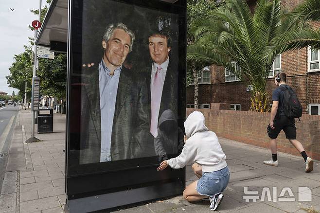 [런던=AP/뉴시스]영국의 한 활동가가 자살한 성범죄자 제프리 엡스타인(왼쪽)과 젊은 시절의 도널드 트럼프 미 대통령이 함께 찍은 사진을 런던 거리에 걸고 있다. 2025.07.24.