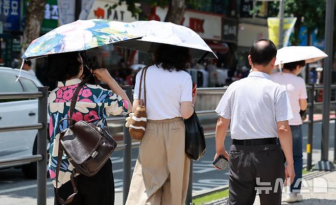 [서울=뉴시스] 이영환 기자 = 시민들이 22일 오후 서울 시내의 한 거리에서 양산으로 강한 햇빛을 피하며 걸어가고 있다. 2025.07.22. 20hwan@newsis.com