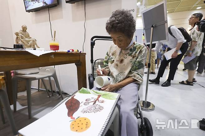[서울=뉴시스] 김근수 기자 = 서울일러스트레이션페어V.19 2025 개막 첫 날인 24일 서울 강남구 코엑스에서 한 어르신 작가가 그림을 그리고 있다. 2024.07.24. ks@newsis.com