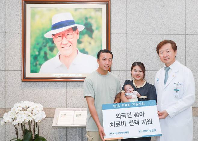 유창식 병원장과 환아의 가족이 고(故) 정주영 아산사회복지재단 설립자의 사진 앞에서 기념촬영을 하고 있다.