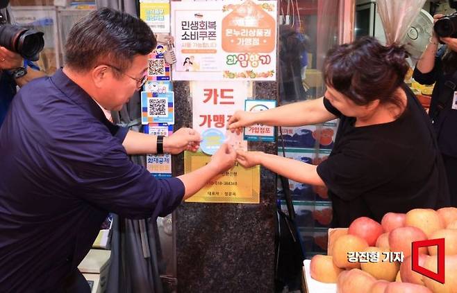 윤호중 행정안전부 장관이 24일 서울 금천구 비단길현대시장을 찾아 민생회복 소비쿠폰 사용 가능 매장 스티커를 부착하고 있다. 강진형 기자