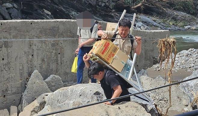 지게로 구호품 나르는 신희섭(가운데)·박수완(검은 옷) 주무관. 경기도 제공