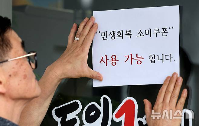 [대구=뉴시스] 이무열 기자 = 민생회복 소비쿠폰 신청 이틀재인 22일 대구 중구 한 음식점 주인이 출입문에 민생회복 소비쿠폰 사용 가능 안내문을 붙이고 있다. 2025.07.22. lmy@newsis.com