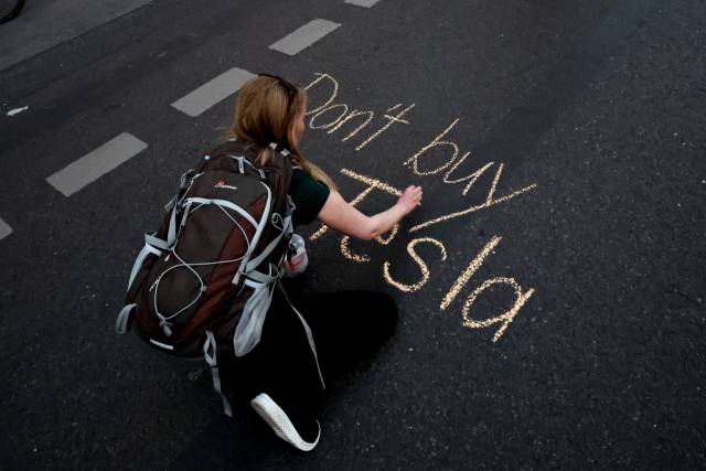 올 4월 30일(현지 시간) 독일 베를린에 위치한 테슬라 매장 앞 대로에 한 시위자가 ‘테슬라를 사지 마세요’라고 쓰고 있다. EPA연합뉴스