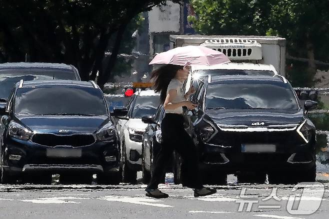 폭염이 연일 계속되는 25일 오후 대구 중구 달구벌대로에서 양산을 쓴 시민이 아지랑이가 피어오르는 도로를 건너고 있다. 2025.7.25/뉴스1 ⓒ News1 공정식 기자