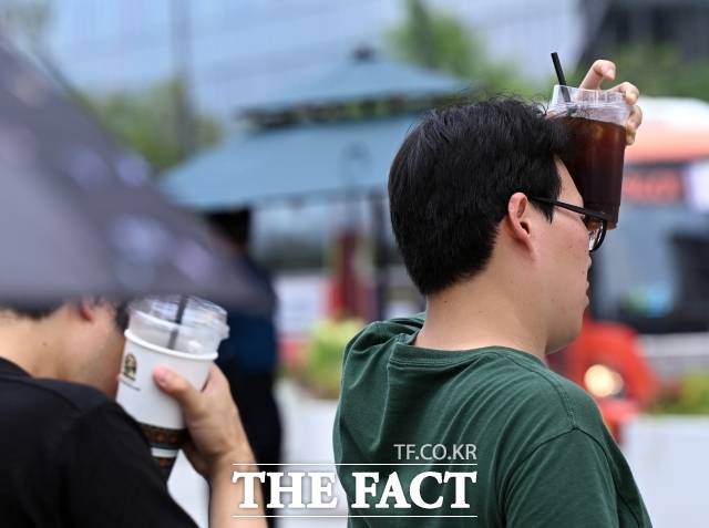 전국 대부분 지역에 폭염특보가 내려진 8일 오후 서울 광화문 일대에서 시민들이 얼음이 든 음료를 얼굴에 가져다 대고 있다./이새롬 기자