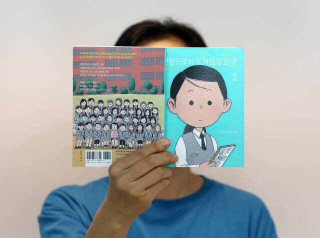 신작 ‘반장으로서의 책임과 의무’를 연재 중인 수신지 작가. 얼굴을 드러내지 않는 그는 이날도 책 표지로 얼굴을 가리고 인터뷰했다. 백소아 기자 thanks@hani.co.kr