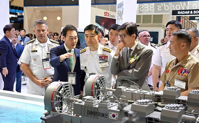 지난 5월 부산 벡스코에서 열린 MADEX 2025에서 유상철(왼쪽 두번재) HJ중공업 대표이사가 고속상륙정에 대해 설명하고 있다. [HJ중공업 제공]