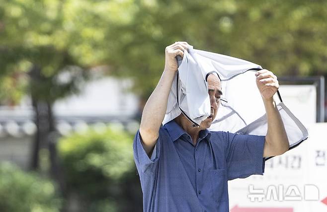 [서울=뉴시스] 김근수 기자 = 연일 이어지는 무더위 속에 26일 서울 중구 남산한옥마을을 찾은 한 관람객이 겉옷으로 햇볕을 가리며 걸어가고 있다. 2024.07.26. ks@newsis.com