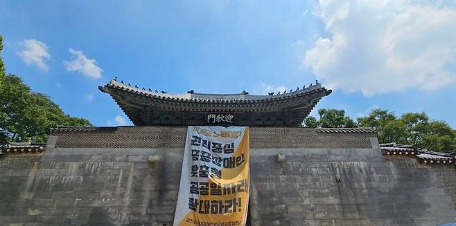 [서울=뉴시스]서울 종로구 경복궁에 대형 현수막을 내건 전국장애인차별철폐연대(전장연) 활동가가 경찰에 붙잡혔다. 서울 종로경찰서는 25일 문화유산법 위반 등 혐의로 전장연 활동가 3명을 이날 현행범 체포했다고 밝혔다. 이들은 같은 날 낮 12시20분께 경복궁 서쪽 대문인 영추문에 올라 '이것도 노동이다! 권리중심 중증장애인 맞춤형 공공일자리 확대하라!'고 적힌 현수막을 펼쳐 게시한 혐의를 받는다. (사진=전장연 제공) 2025.07.25. photo@newsis.com *재판매 및 DB 금지