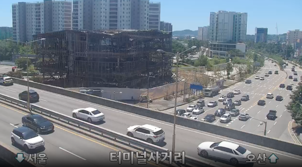 27일 새벽 경기 수원시 권선동에 있는 아파트 모델하우스에 불이 났다. 사진은 오전 11시 30분 앙상한 철근 구조만 남은 화재 건물. [사진 = 도로공사 CCTV 갈무리]