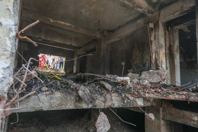 방글라데시 사람들이 2025년 7월 22일 방글라데시 다카의 마일스톤 칼리지 캠퍼스에 공군 훈련용 항공기가 추락한 후 불에 탄 학교 건물을 바라보고 있다. 7월 21일 다카의 마일스톤 스쿨 앤 칼리지에서 발생한 항공기 추락 사고로 인한 사망자 수가 31명으로 증가했다. 이 사고로 165명이 부상을 입었다. EPA연합뉴스