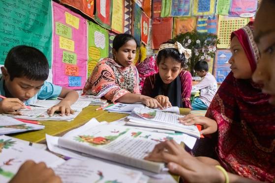 다카에 위치한 대안학교에서 교사 아끌리마 압달 아크리(32)가 지난 8일 아이들과 함께 벵골어 교재를 읽고 있다. 사진 유니세프