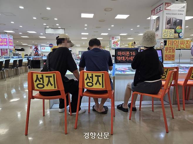 27일 신도림테크노마트 휴대전화 집단상가를 찾은 한 가족이 계약서를 작성하고 있다. 송윤경 기자