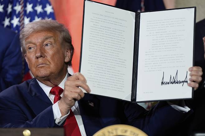 U.S. President Donald Trump holds a signed executive order permitting AI infrastructure after speaking during an AI summit at the Andrew W. Mellon Auditorium in Washington on July 23. [AP/YONHAP]