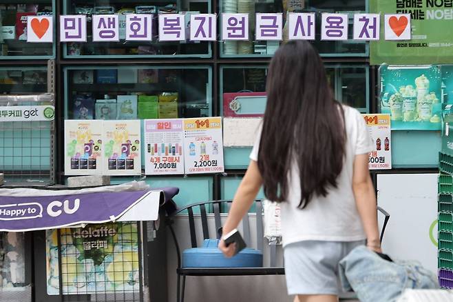 행인이 지난 13일 민생회복 소비쿠폰 사용처 안내문이 붙은 편의점 옆을 지나가고 있다. 연합뉴스