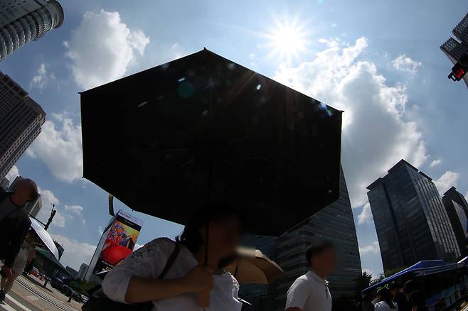 27일 서울의 낮 최고 기온이 37도까지 오르는&nbsp;등 가마솥 더위가 전국을 달구고 있다. 사진은 서울 시내에서 한 시민이 양산을 쓰고 이동하고 있는 모습. 뉴시스