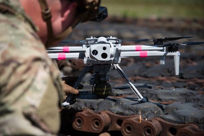 지상에서 수류탄 장착 중인 드론 클로즈업 - 병사가 M67 수류탄을 장착한 스카이디오 X10D 드론을 점검하고 있다. 드론에는 미 육군 전투역량개발사령부가 개발한 자동화 투하 장비 ‘오디블 드로퍼’가 장착돼 있다. 출처=미 육군