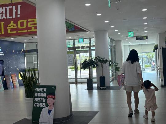 28일 대전 서구 관저동 대전어린이공공재활병원에서 열린 전국보건의료산업노동조합 대전충남지역본부 총파업 집회 옆을 한 부모와 아이가 지나고 있다. 최다인기자
