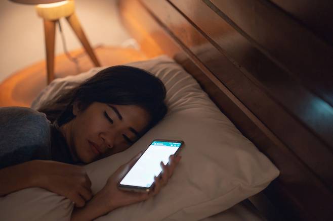 A woman falls asleep while holding her mobile phone. (123rf)