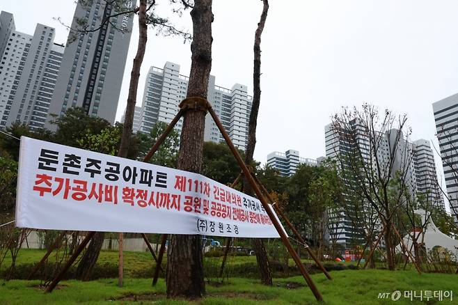 [서울=뉴시스] 황준선 기자 = 22일 서울 강동구 올림픽파크포레온 단지에 공사중단을 알리는 현수막이 게시돼 있다.   입주를 한 달여 앞둔 서울 강동구 둔촌주공 재건축(올림픽파크포레온)은 재건축 현장 주변 도로와 조경 등 기반시설을 담당 시공사들의 추가 공사비 요구를 조합이 거부하며 지난 19일부터 공사가 중단됐다.  2024.10.22. hwang@newsis.com /사진=황준선