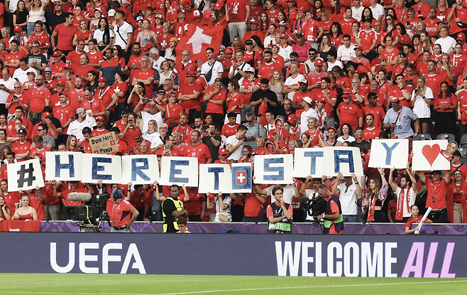 스위스 팬들이  지난 18일, UEFA 여자 유로 2025 8강전 스페인0스위스전에 앞서 ‘#heretostay(여성축구는 여기 남는다)’라는 문구가 적힌 대형 티포를 펼치고 있다. 게티이미지