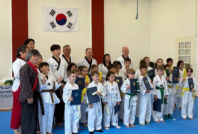 김우현 사범 가족과 수련생들 김우현 사범 가족과 태권도 수련생들이 독일 라인펠덴시에 있는 태권도장에서 기념 사진을 찍고 있다. 앞줄 맨 왼쪽부터 시계방향으로 김 사범의 아버지, 큰 여동생, 큰형, 작은 여동생, 작은형. [김우현 사범 제공]
