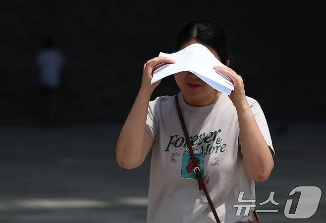 서울 전역에 폭염경보가 내려진 24일 서울 용산구 국립중앙박물관에서 시민이 종이로 뜨거운 햇빛을 가리고 있다. 2025.7.24/뉴스1 ⓒ News1 김민지 기자