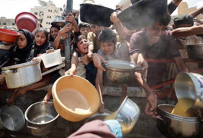 28일(현지시각) 가자 북부 가자시티 팔레스타인 주민들이 음식을 받기 위해 기다리고 있다. 가자시티/로이터 연합뉴스