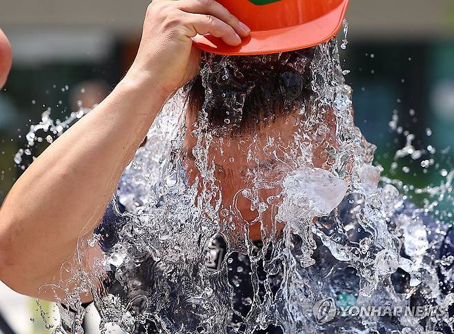 '더위야, 가라!' (서울=연합뉴스) 김도훈 기자 = 29일 서울 종로구 국정기획위원회 앞에서 열린 민주노총 건설노조 폭염 실태 기자회견이 끝난 뒤 참가자가 얼음물을 뒤집어쓰는 퍼포먼스를 하고 있다. 2025.7.29 superdoo82@yna.co.kr