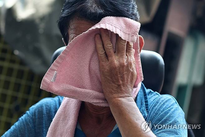 폭염 (서울=연합뉴스) 윤동진 기자 = 폭염이 이어지고 있는 28일 서울 동대문종합시장 인근에서 한 근로자가 원단을 옮긴 후 땀을 닦으며 휴식을 취하고 있다. 2025.7.27 mon@yna.co.kr