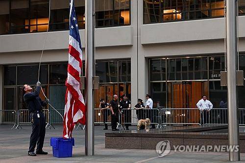 뉴욕 총기 난사 건물 앞에서 조기 게양하는 남성 [로이터=연합뉴스]