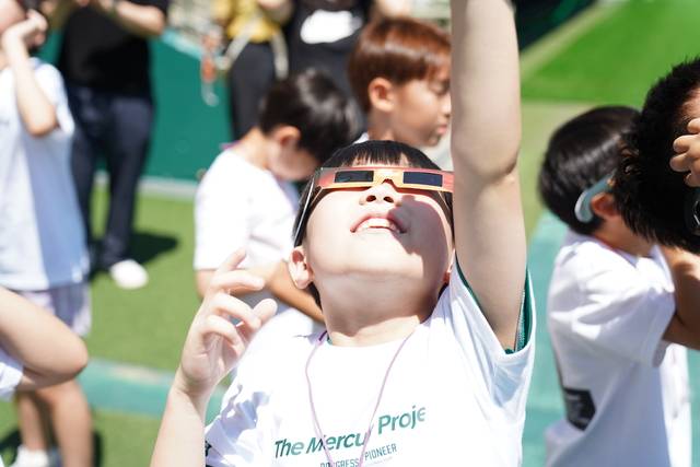 전북현대모터스FC·국립전북기상과학관(전주기상지청)이 공동 기획한 '머큐리 프로젝트' 2기 활동에 참여한 만성초등학교 3학년 학생이 30일 전주월드컵경기장에서 직접 만든 태양 관측용 종이 소재 안경을 쓰고 태양을 바라보고 있다. 전북현대 제공