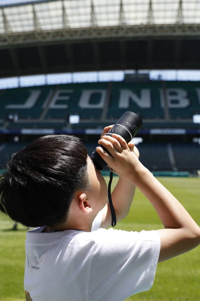 전북현대모터스FC·국립전북기상과학관(전주기상지청)이 공동 기획한 '머큐리 프로젝트' 2기 활동에 참여한 만성초등학교 3학년 학생이 30일 전주월드컵경기장에서 단망경을 들고 태양을 관측하고 있다. 전북현대 제공
