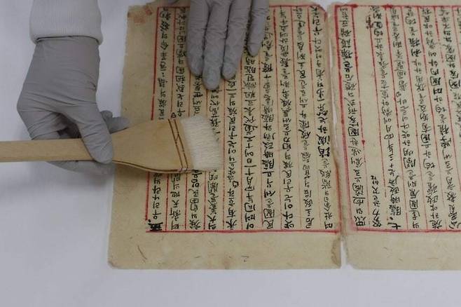 대한민국임시정부 건국강령 초안의 보존처리 작업 모습. 겉 지면의 오염물을 붓질하며 걷어내는 장면이다. 국가문화유산연구원 제공