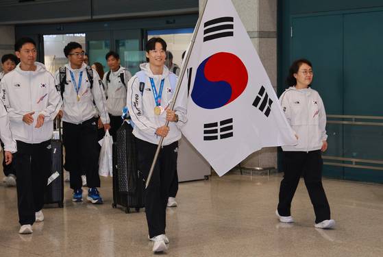 Korea's men's 4x100-meter relay team members, including Seo Min-jun, Joel Jin Nwamadi, Lee Jae-sung and Kim Jeong-yun walk with the Korean flag upon arrival at Incheon International Airport on July 29. [YONHAP]